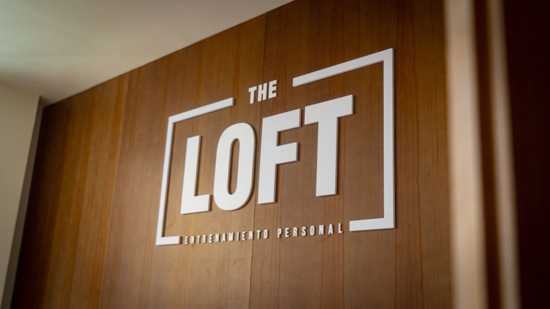 Logo de The Loft en relieve sobre la pared de madera del estudio